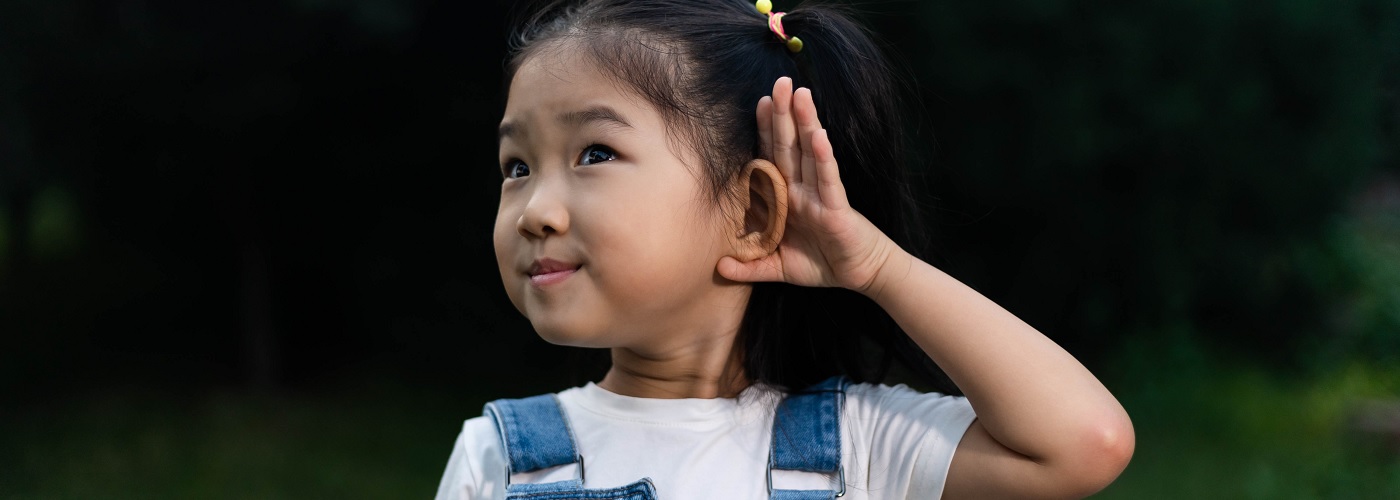 A young girl cupping her ear