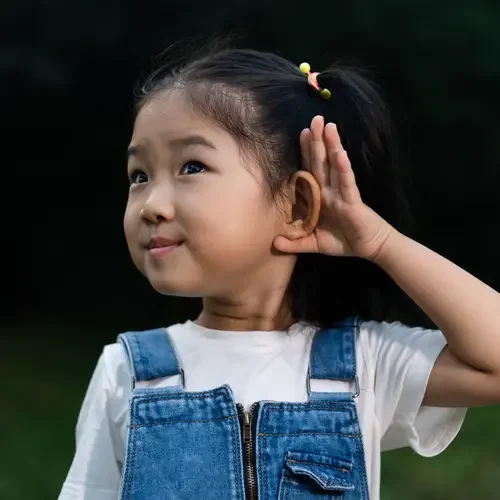 A young girl cupping her ear