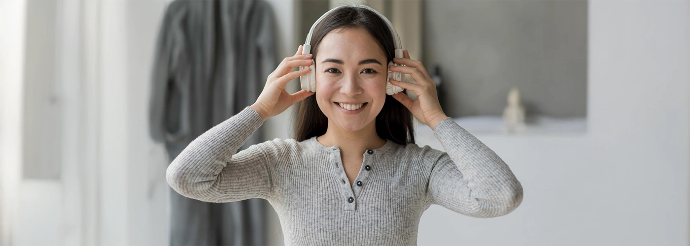 Seorang wanita melaraskan kelantangan bunyi pada fon kepala untuk mengelakkan gegendang telinga pecah