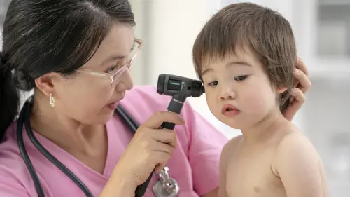 An ENT specialist examining a young child&#39;s ear